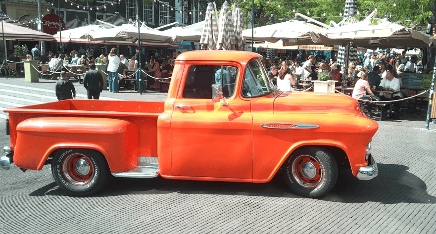 Classic orange pickup truck parked at outdoor festival in The Hague.