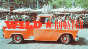 Vintage orange truck with Wild Rooster logo at The Hague festival.